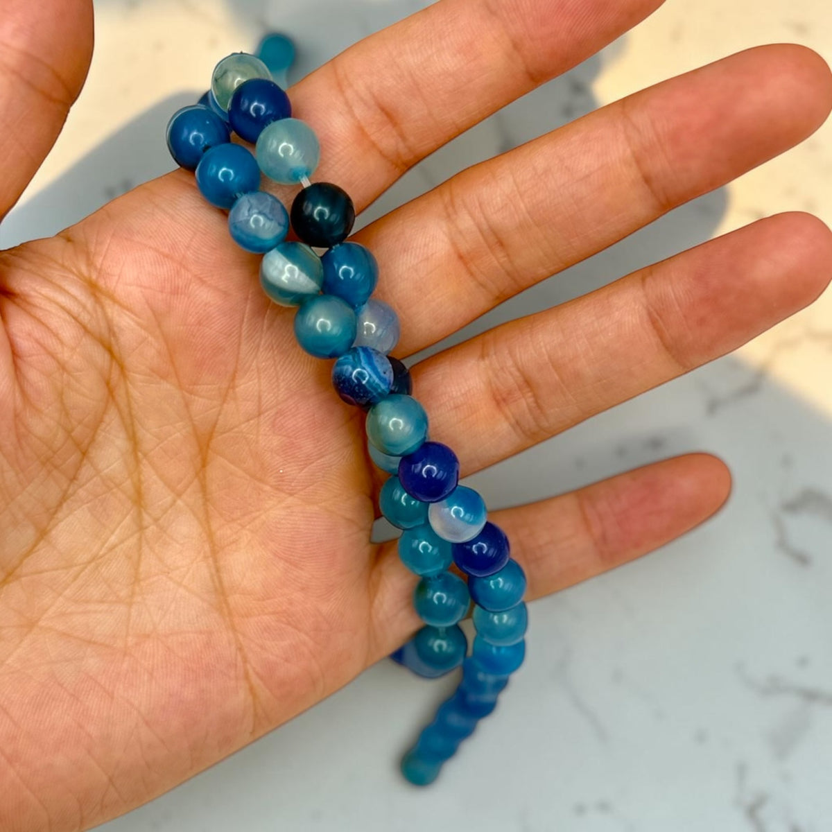 Close-up of striped blue agate beads in hand