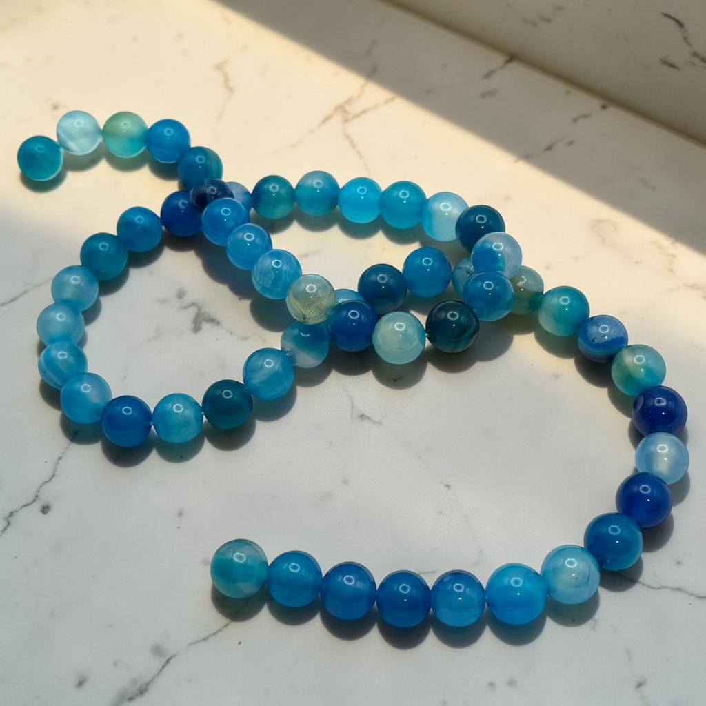 Striped blue agate bead strand showing natural blue color variation
