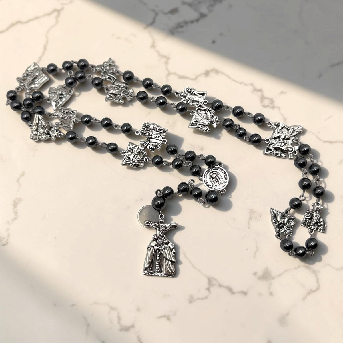 Full Way of the Cross chaplet with dark gray hematite beads, silver Stations of the Cross medals, Holy Face of Jesus centerpiece, and silver crucifix