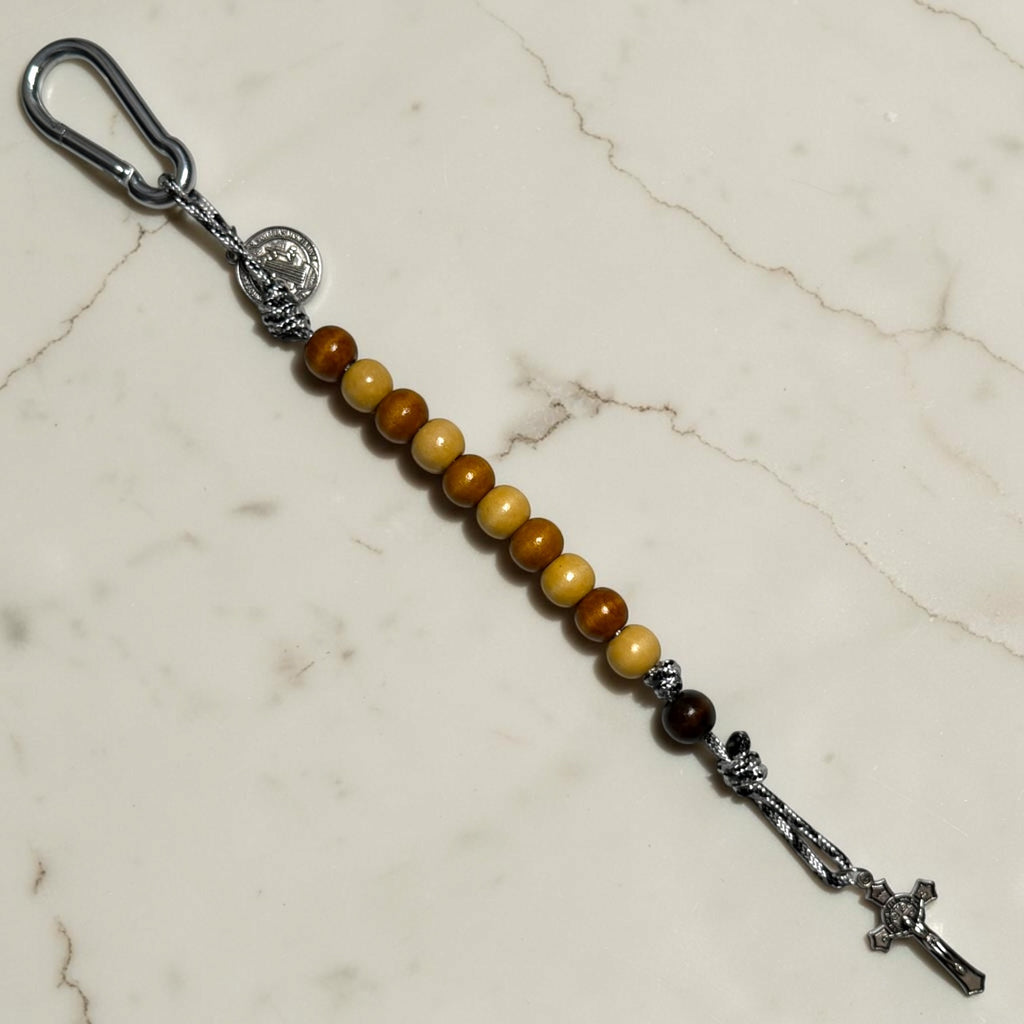 Full-length Saint Benedict decade rosary with alternating beige and brown wood beads, black and white paracord, dark brown Our Father bead, carabiner, medal, and crucifix
