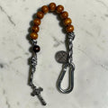 Saint Benedict decade rosary with warm brown wood beads, dark brown Our Father bead, black and white paracord, carabiner, medal, and crucifix