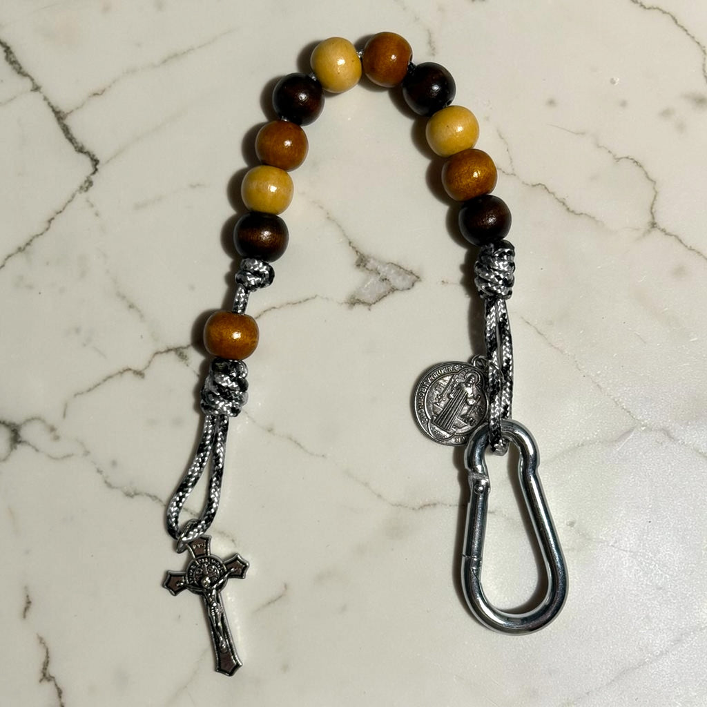 Saint Benedict decade rosary with dark brown, warm brown, and beige wood beads, brown Our Father bead, black and white paracord, carabiner, medal, and crucifix