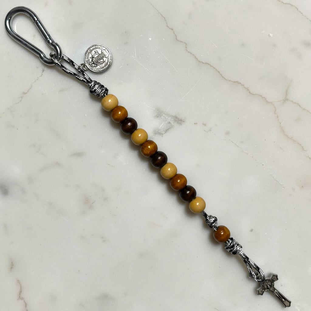 Full-length Saint Benedict decade rosary with repeating beige, medium brown, and dark brown wood bead pattern, black and white paracord, warm brown Our Father bead, carabiner, medal, and crucifix