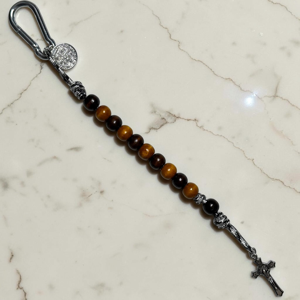 Full-length Saint Benedict decade rosary with alternating dark brown and warm brown wood beads, black and white paracord, dark brown Our Father bead, carabiner, medal, and crucifix