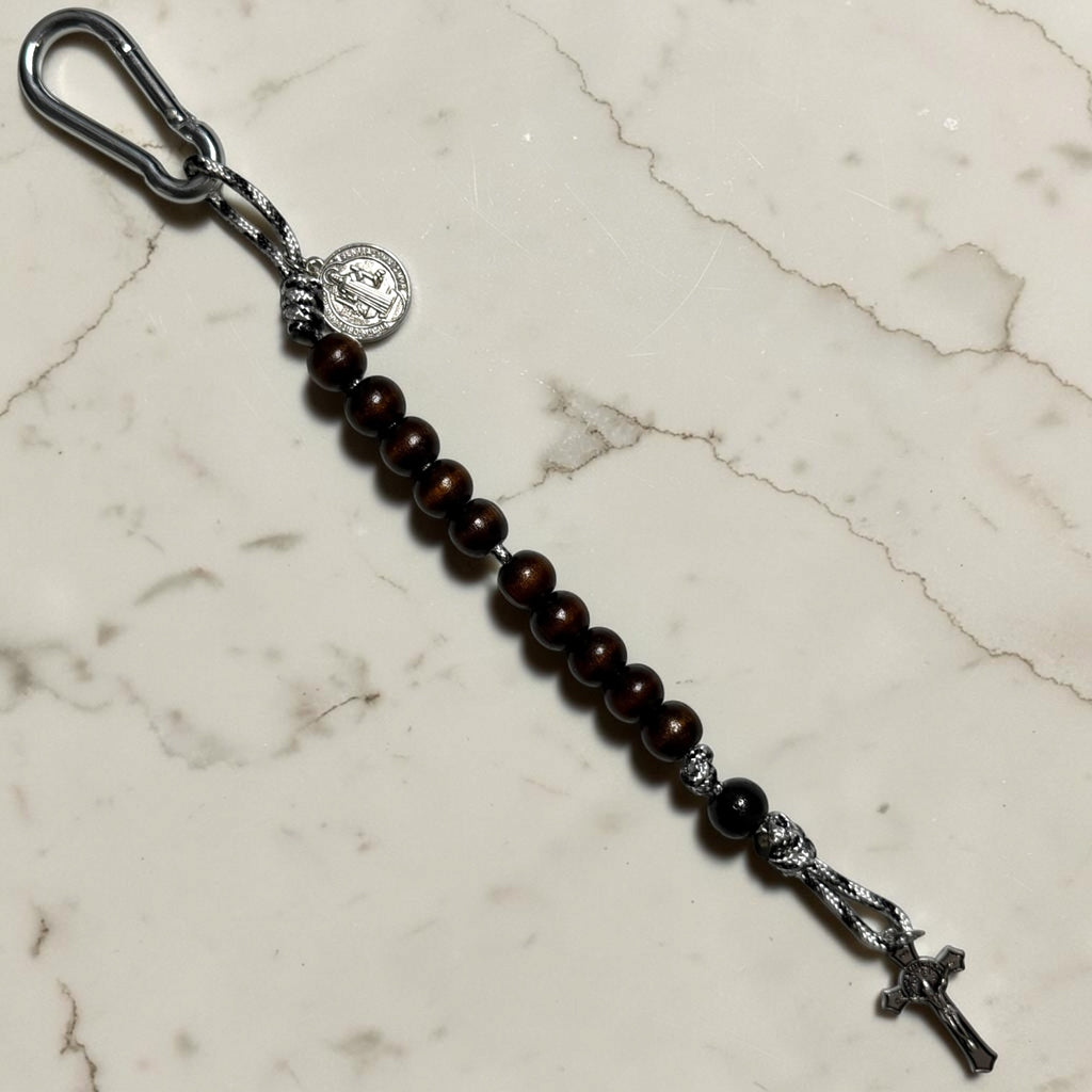 Saint Benedict decade rosary with dark brown wood beads, black Our Father bead, black and white paracord, carabiner, medal, and crucifix