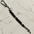 Saint Benedict decade rosary with dark brown wood beads, black Our Father bead, black and white paracord, carabiner, medal, and crucifix