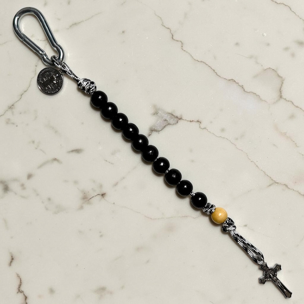 Saint Benedict decade rosary with black wood beads, beige Our Father bead, black and white paracord, carabiner, medal, and crucifix
