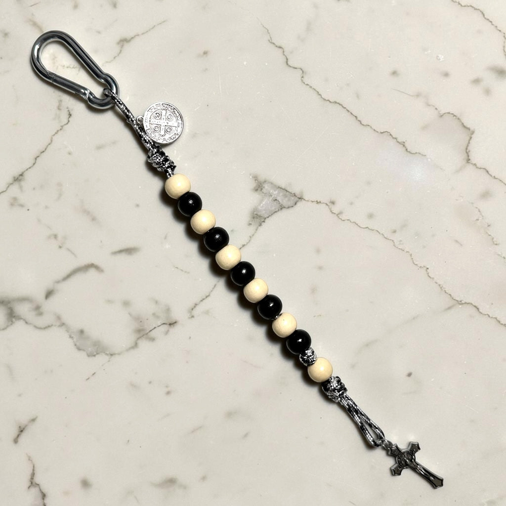 Saint Benedict decade rosary with alternating black and ivory wood beads, ivory Our Father bead, black and white paracord, carabiner, medal, and crucifix