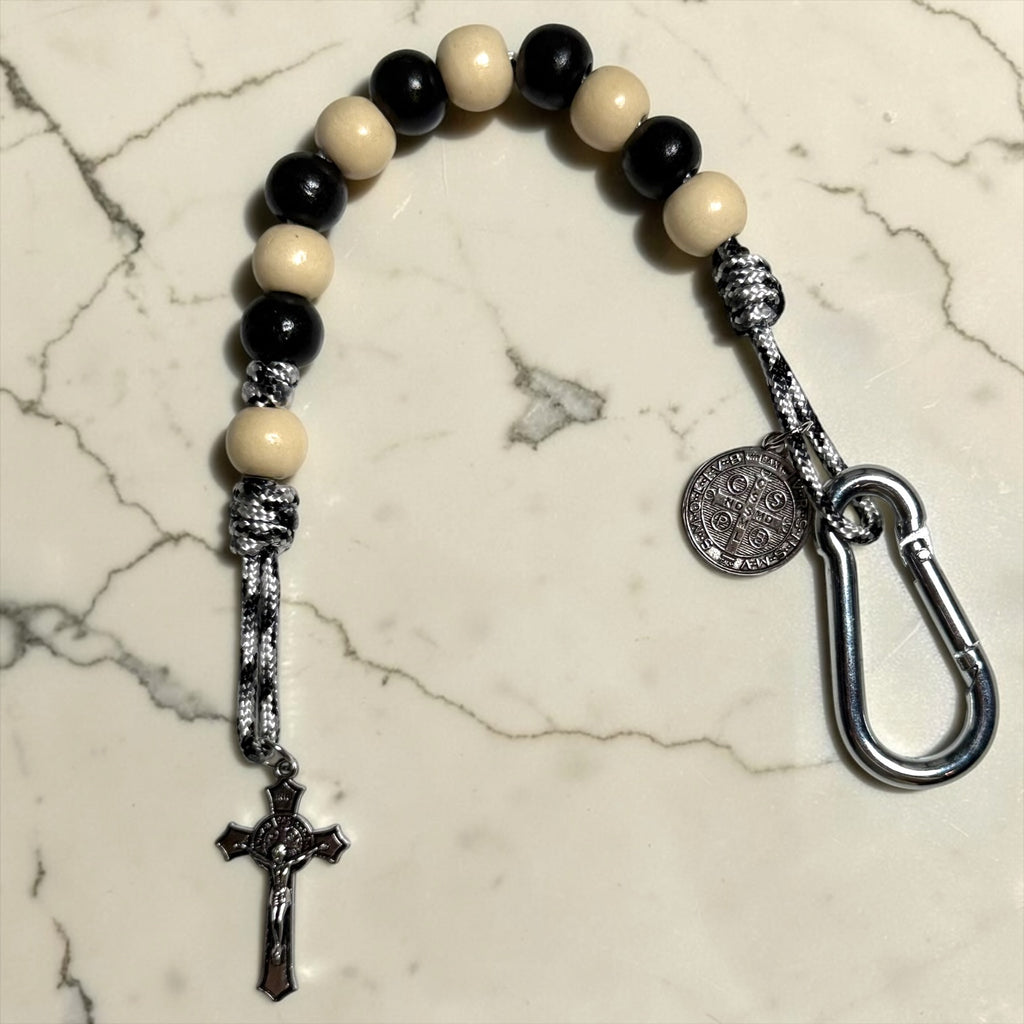 Saint Benedict decade rosary with alternating black and ivory wood beads, ivory Our Father bead, black and white paracord, silver-tone carabiner, medal, and crucifix