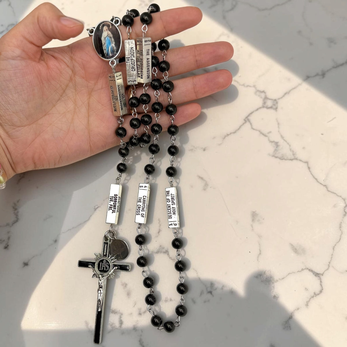 Hand-held black and silver Guided Mystery Rosary with black beads, engraved mystery bars, Our Lady of Lourdes centerpiece, and IHS crucifix