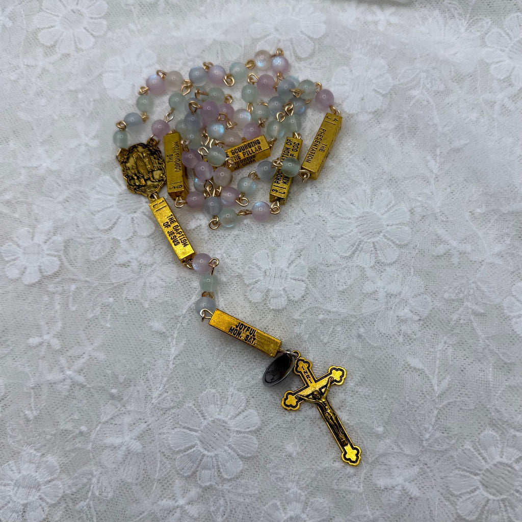 Gold guided mystery rosary arranged on white lace