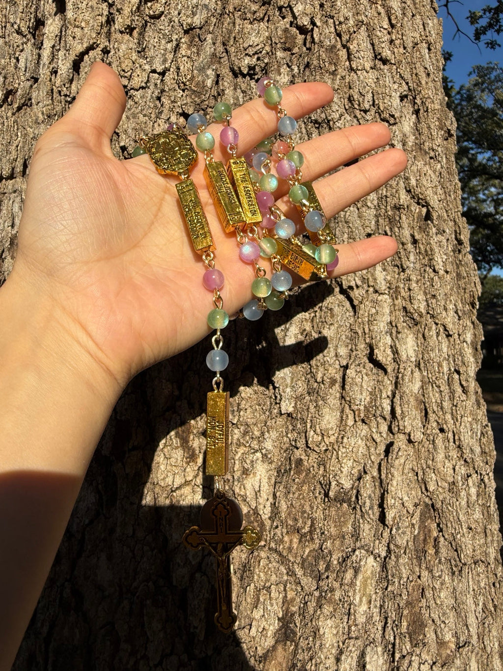 Pastel rosary held outdoors in natural sunlight