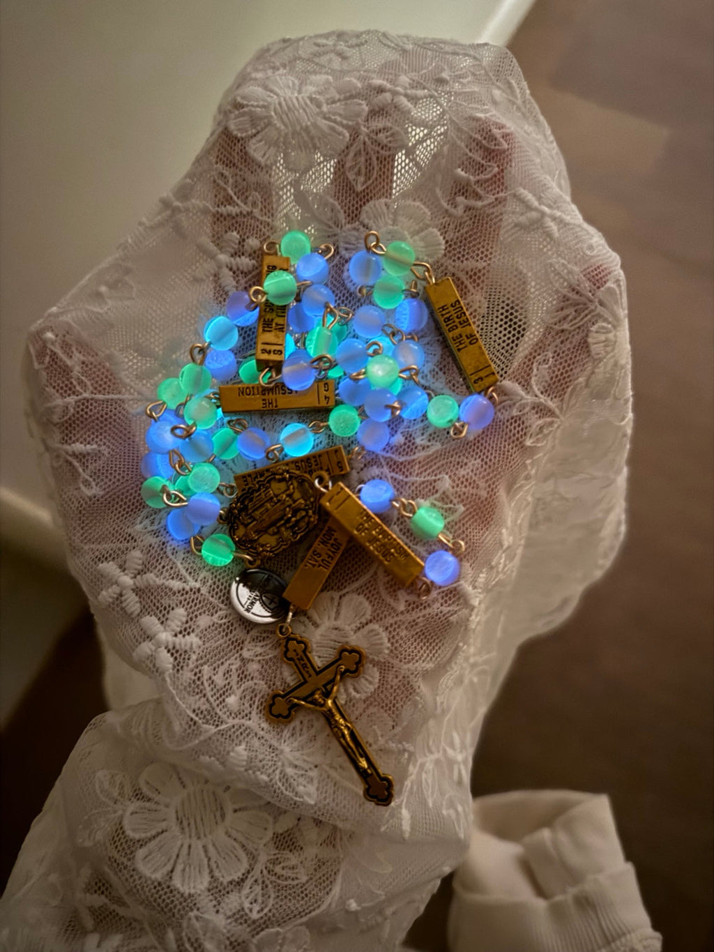 Glowing blue and green rosary on white lace