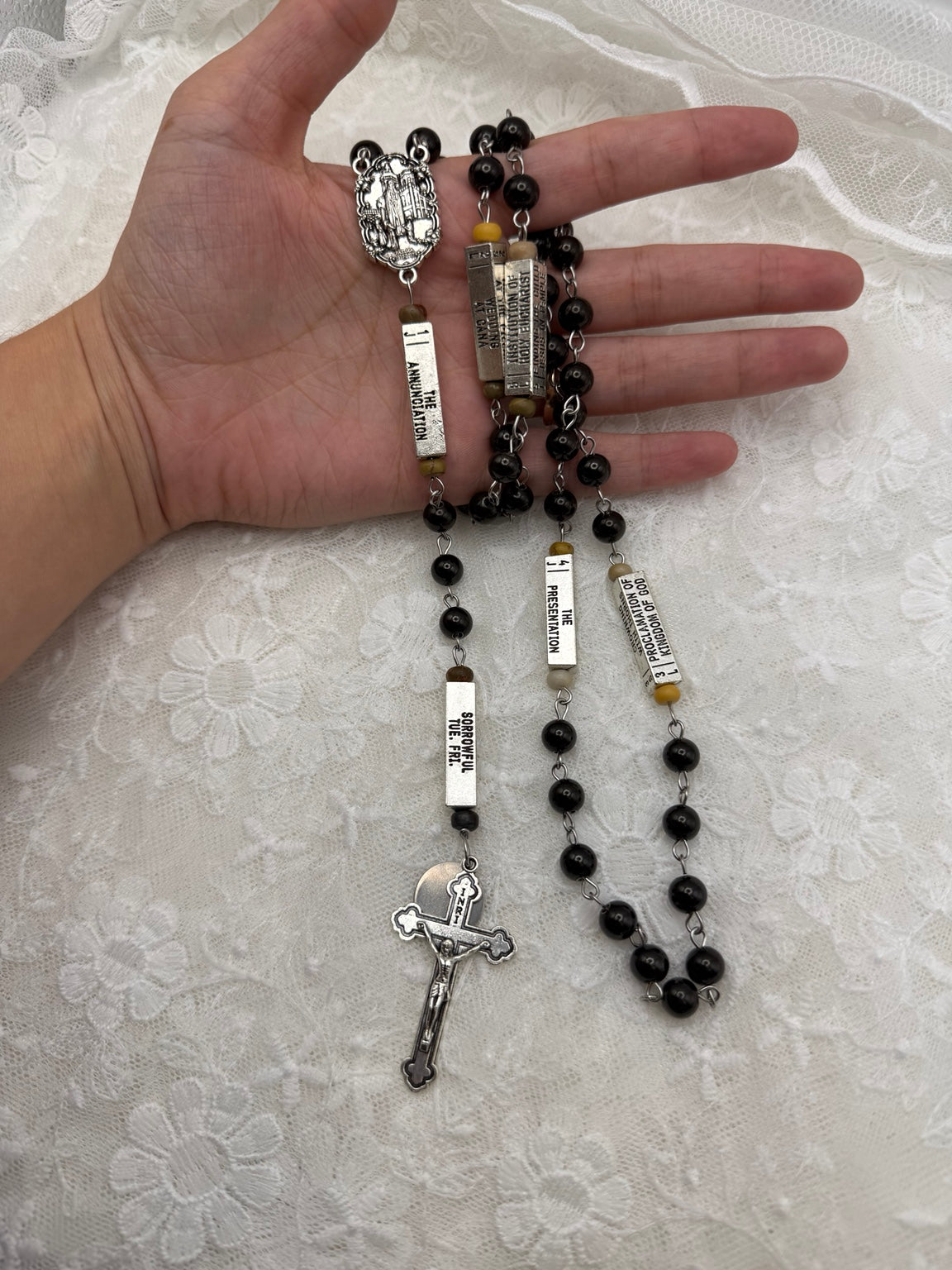 Silver Marian centerpiece and guided mystery rosary held in hand