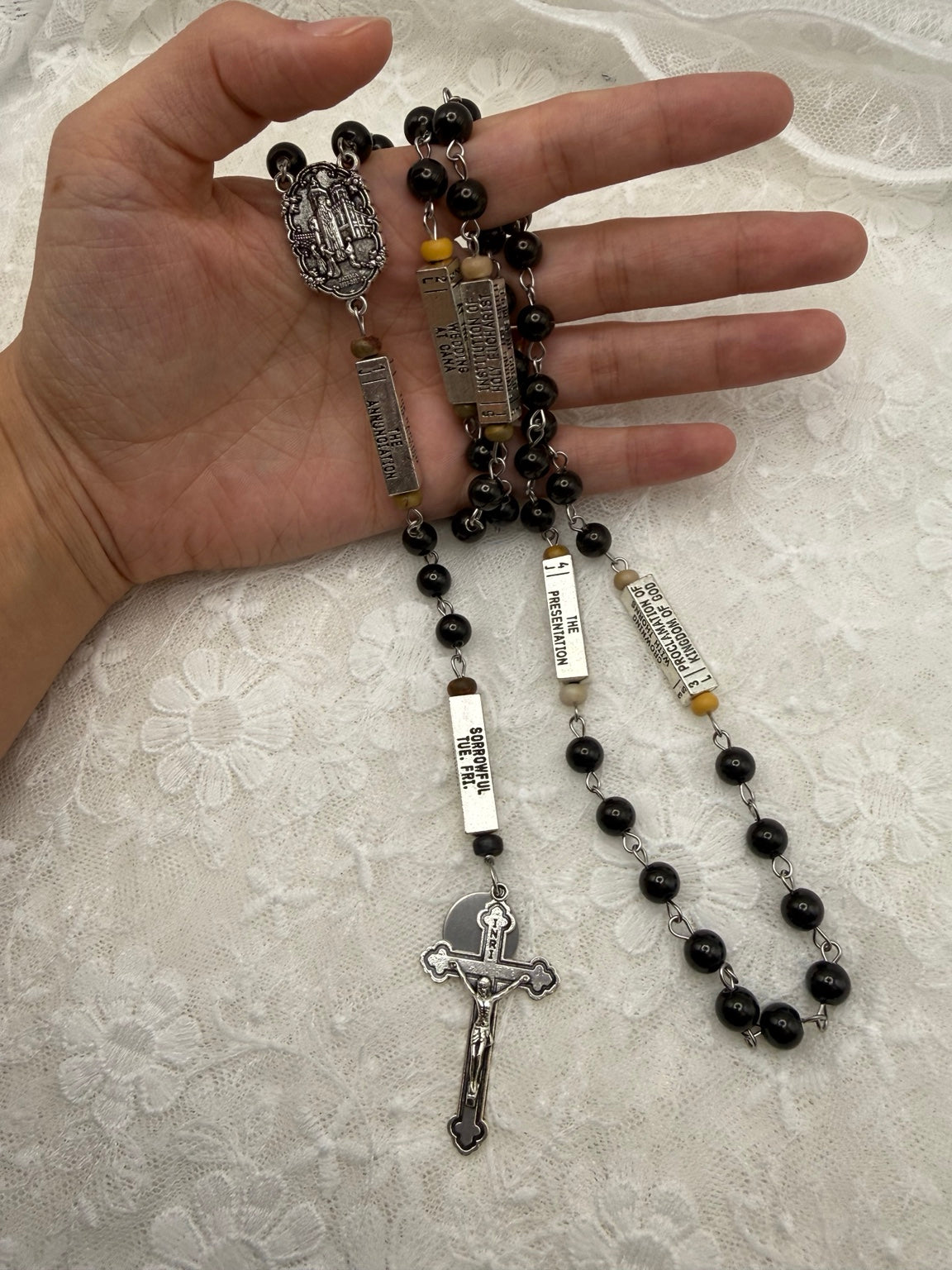 Close-up of silver crucifix and black wood rosary beads