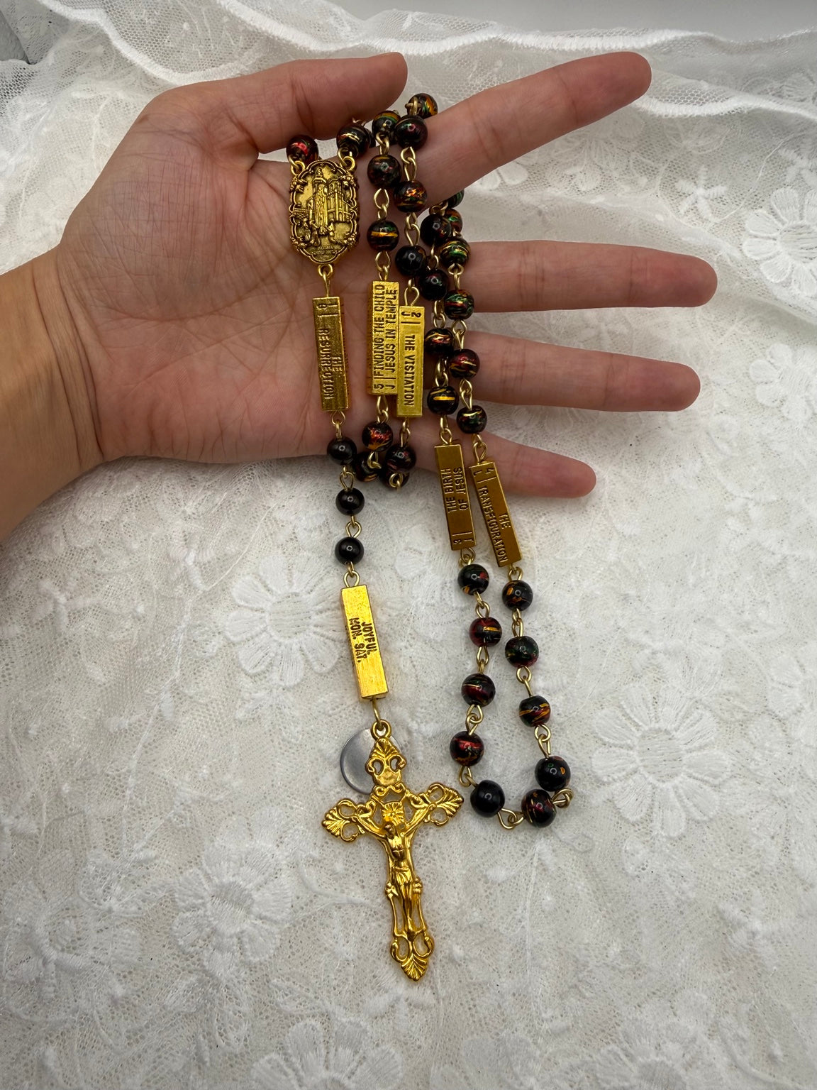 Black multicolor gold rosary held in hand