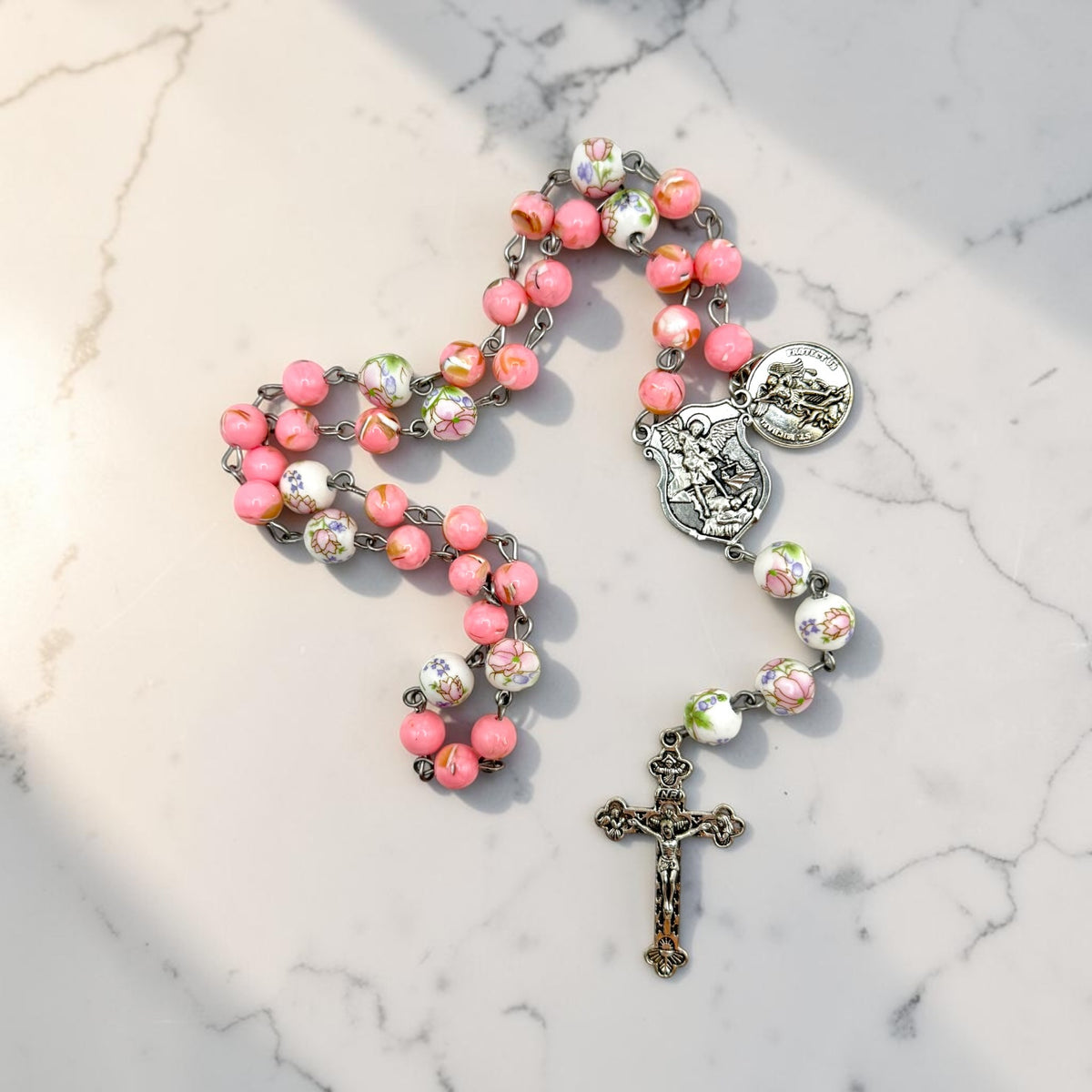 Pink floral St. Michael Chaplet angled view with St. Michael centerpiece