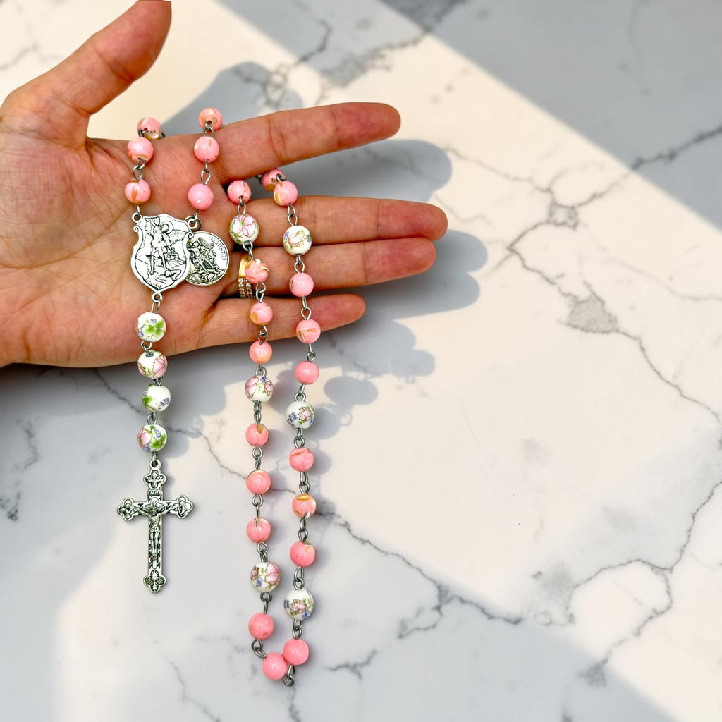 Pink floral St. Michael Chaplet held in hand for scale