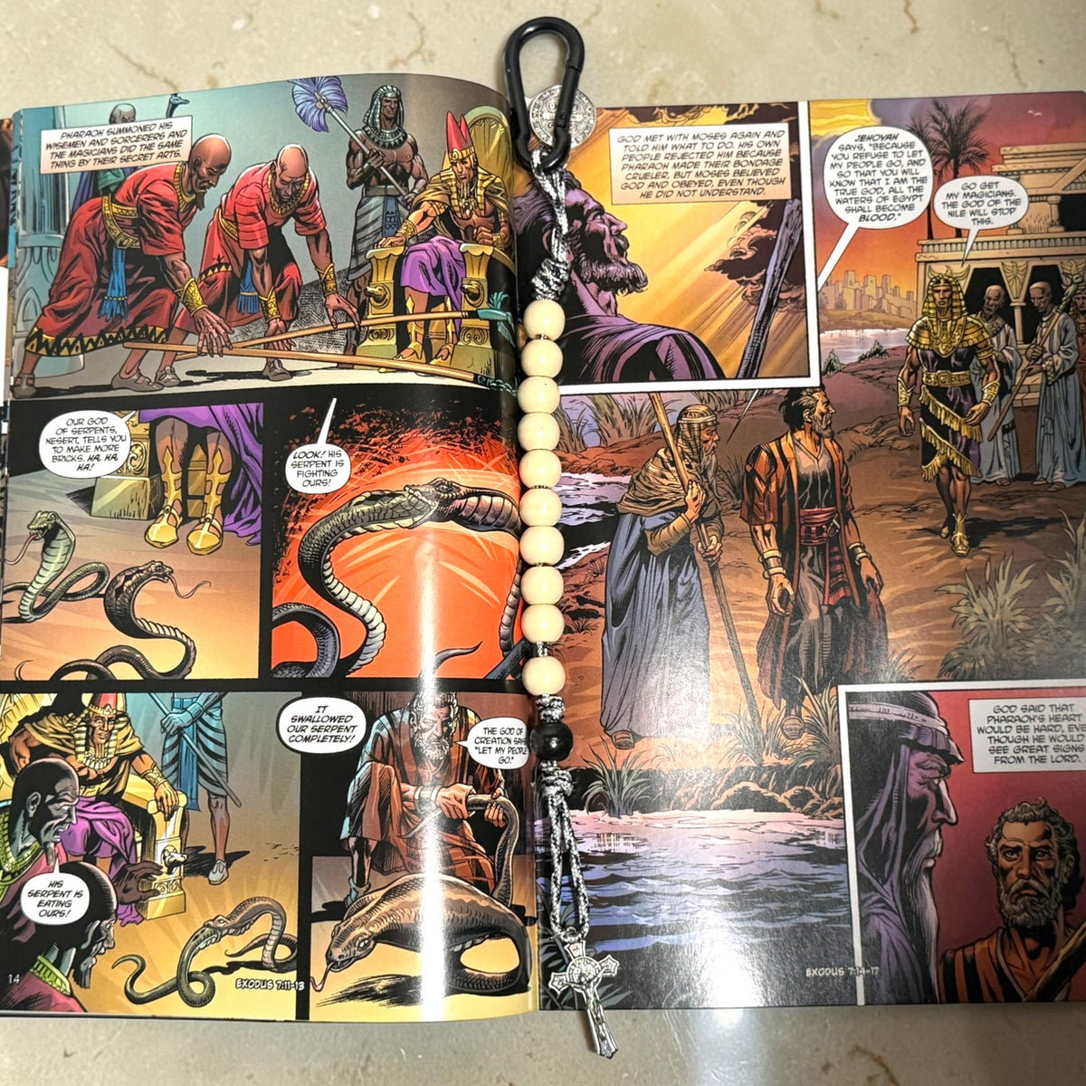 Moses comic book open to Exodus artwork with wooden St. Benedict decade rosary