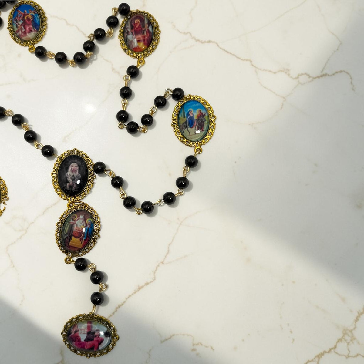 Our Lady of Sorrows chaplet detail with black beads, gold-tone links, and sorrow meditation images