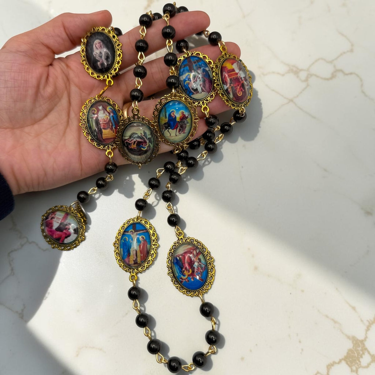 Handheld Our Lady of Sorrows chaplet showing multiple framed meditation images and black beads