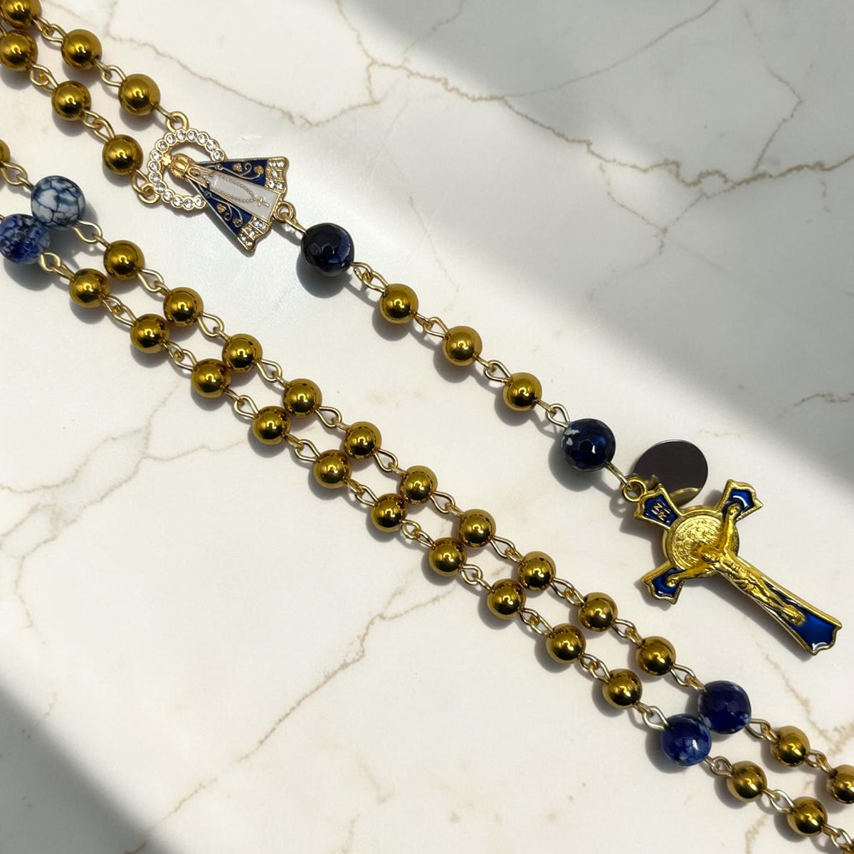 Close-up of Our Lady Aparecida centerpiece and gold-and-blue crucifix on handmade rosary