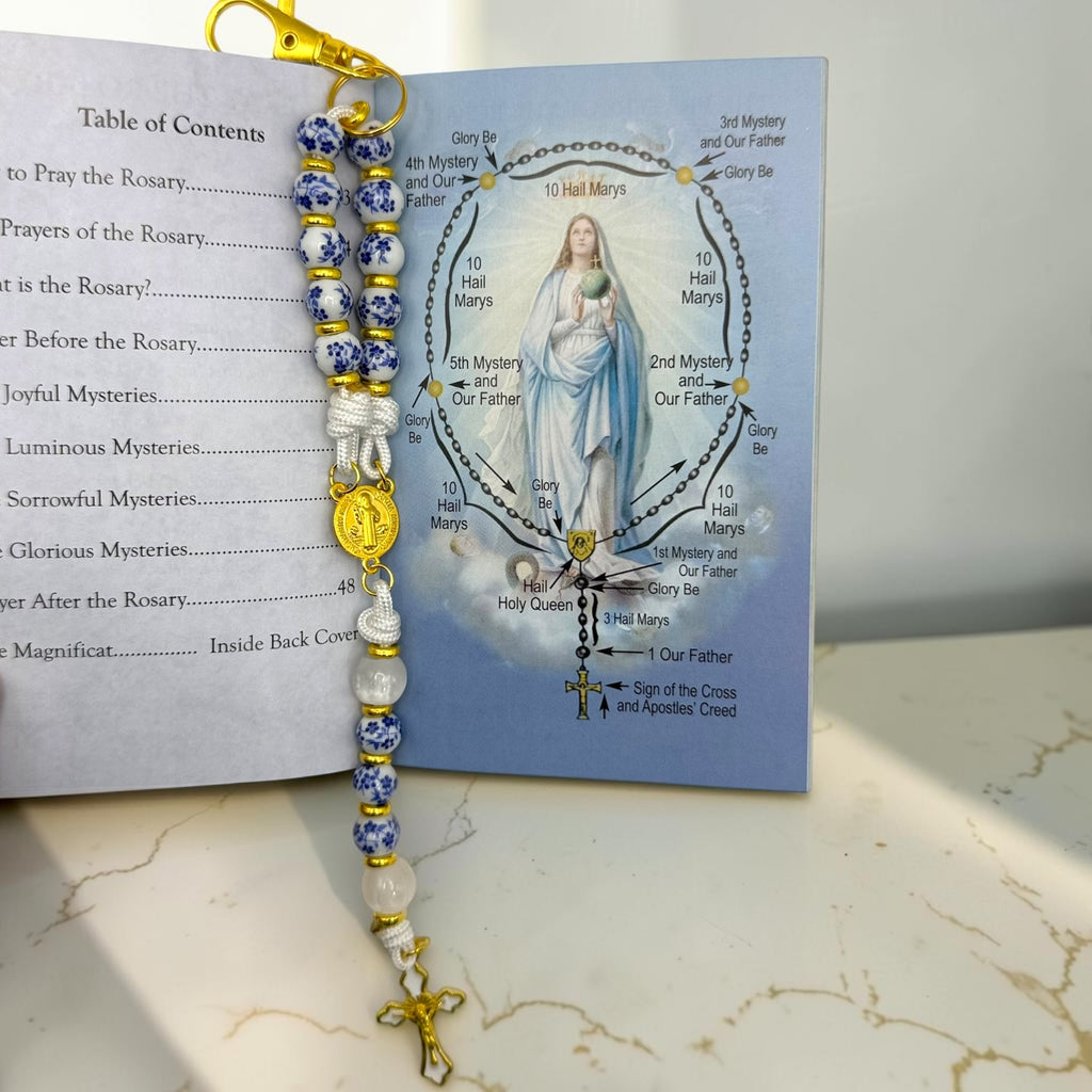 Open How to Pray the Rosary booklet with porcelain decade rosary showing prayer diagram