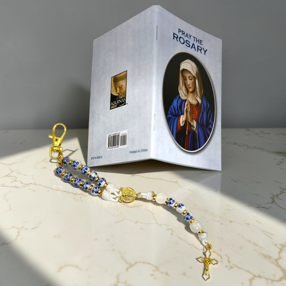 How to Pray the Rosary booklet standing beside blue and white porcelain decade rosary