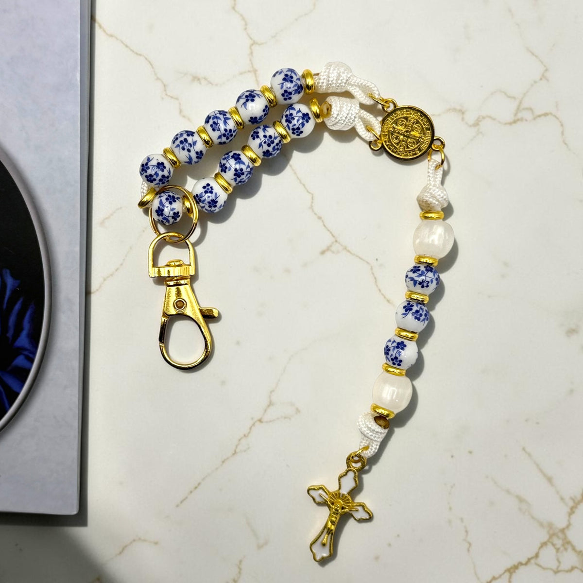 Close-up of blue and white porcelain decade rosary with gold hardware and crucifix