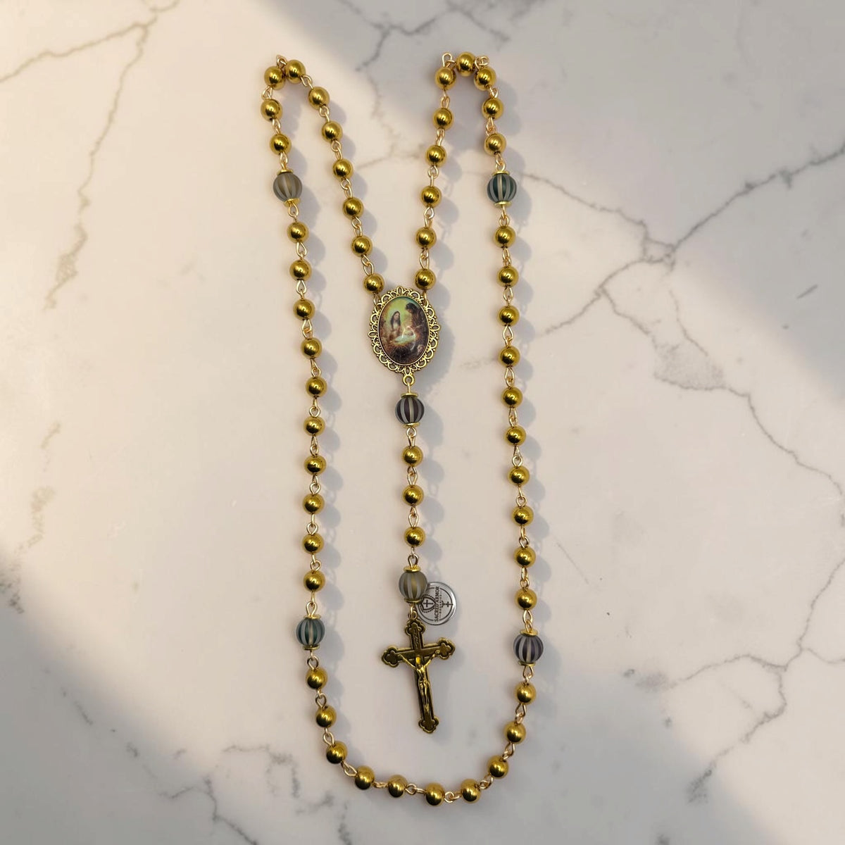 Full gold Holy Family rosary with polished gold-tone beads, striped accent Our Father beads, Holy Family centerpiece, and gold crucifix