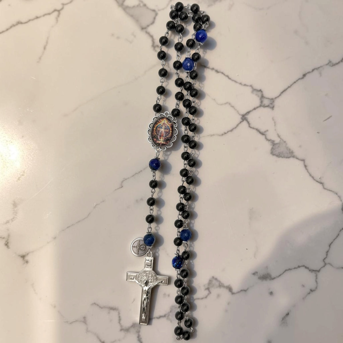 Full black and blue St. Benedict rosary with glossy black beads, deep blue faceted stone accent beads, ornate St. Benedict centerpiece, and silver-tone crucifix
