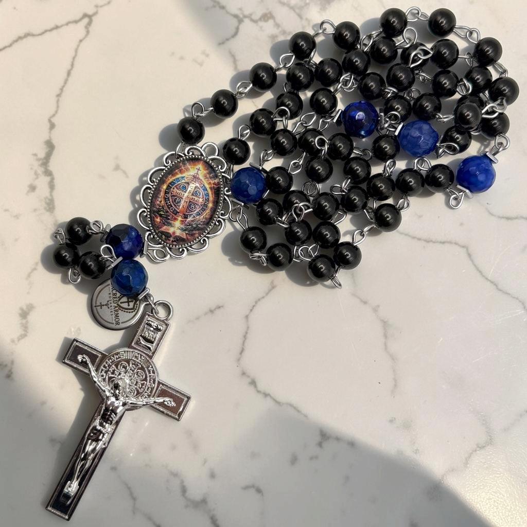 Detailed black and blue St. Benedict rosary showing glossy black beads, deep blue faceted accent stones, ornate St. Benedict centerpiece, Sacred Armor medal, and silver-tone crucifix