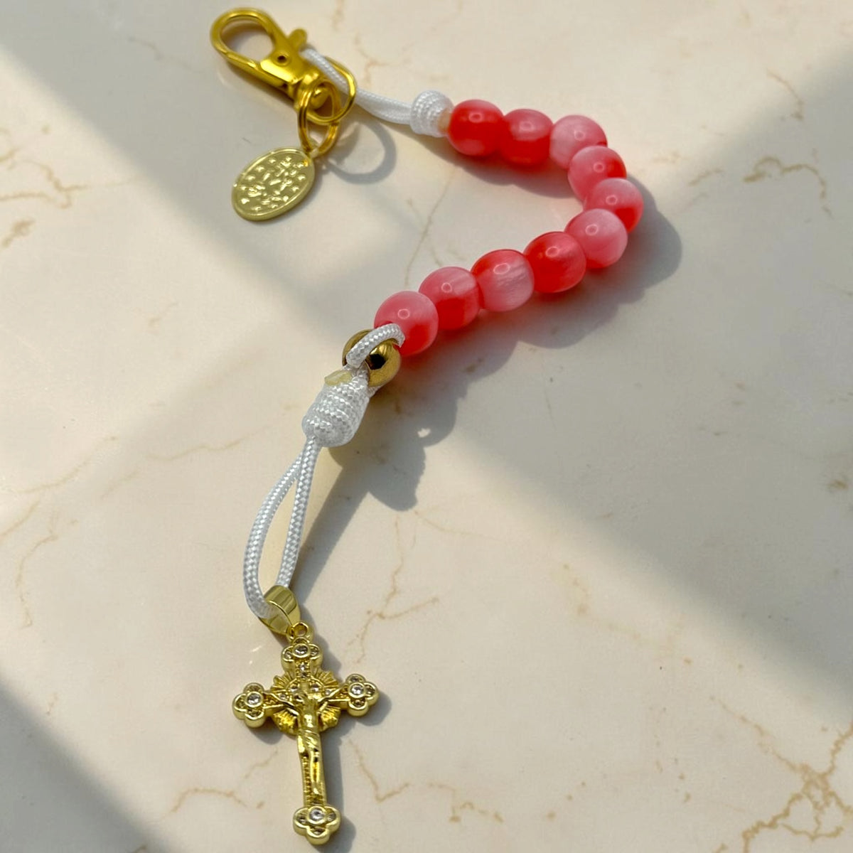 Pink and red Catholic decade rosary with gold-tone crucifix, Marian medal, and portable clasp
