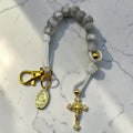 Gray decade rosary with white cord, gold-tone hardware, Marian medal, and crystal crucifix