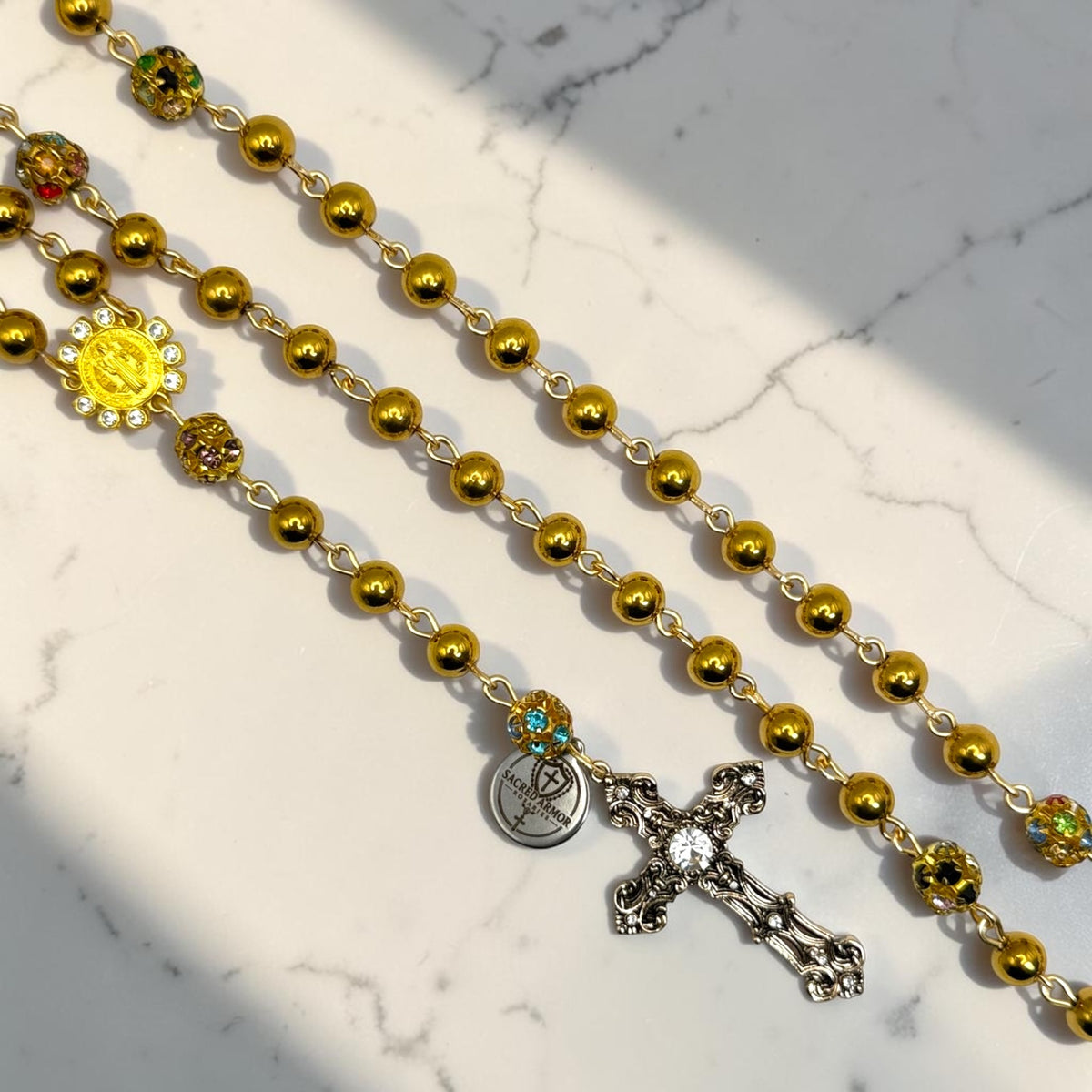 Gold Saint Benedict rosary close-up with crystal gemstone accents