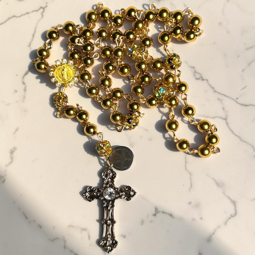 Gold Saint Benedict rosary laid out with crystal gemstone accent beads