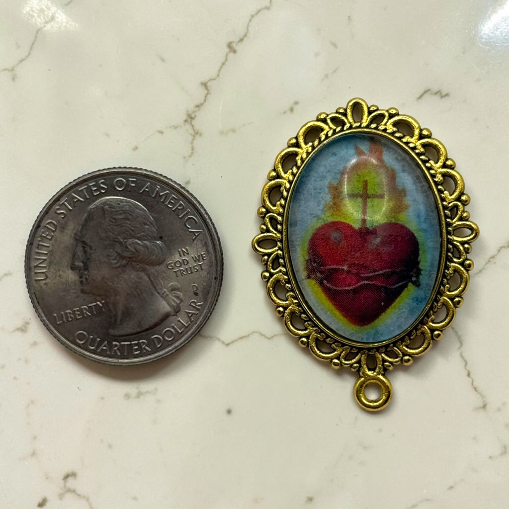 Gold Sacred Heart of Jesus glass cabochon rosary centerpiece shown beside a quarter for scale