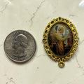 Gold St. Joseph and Child Jesus glass cabochon rosary centerpiece shown beside a quarter for scale