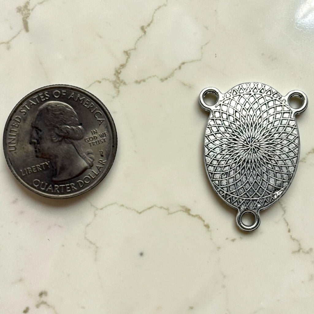 Our Lady of Guadalupe rosary centerpiece silver-tone patterned back shown beside a quarter