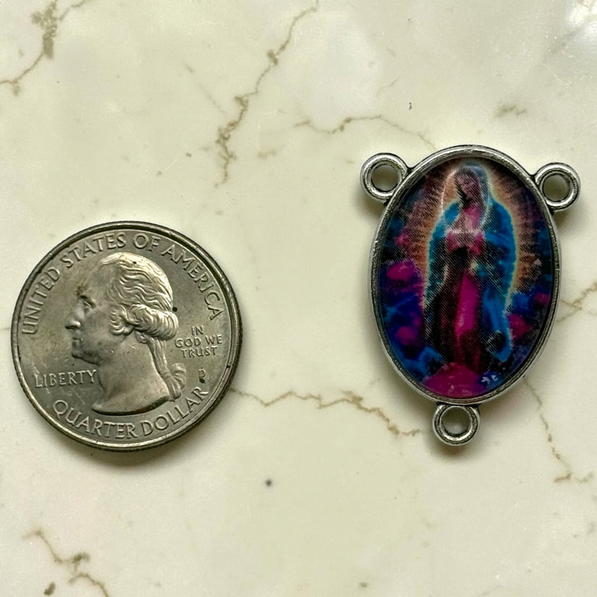 Our Lady of Guadalupe glass cabochon rosary centerpiece shown beside a quarter for scale