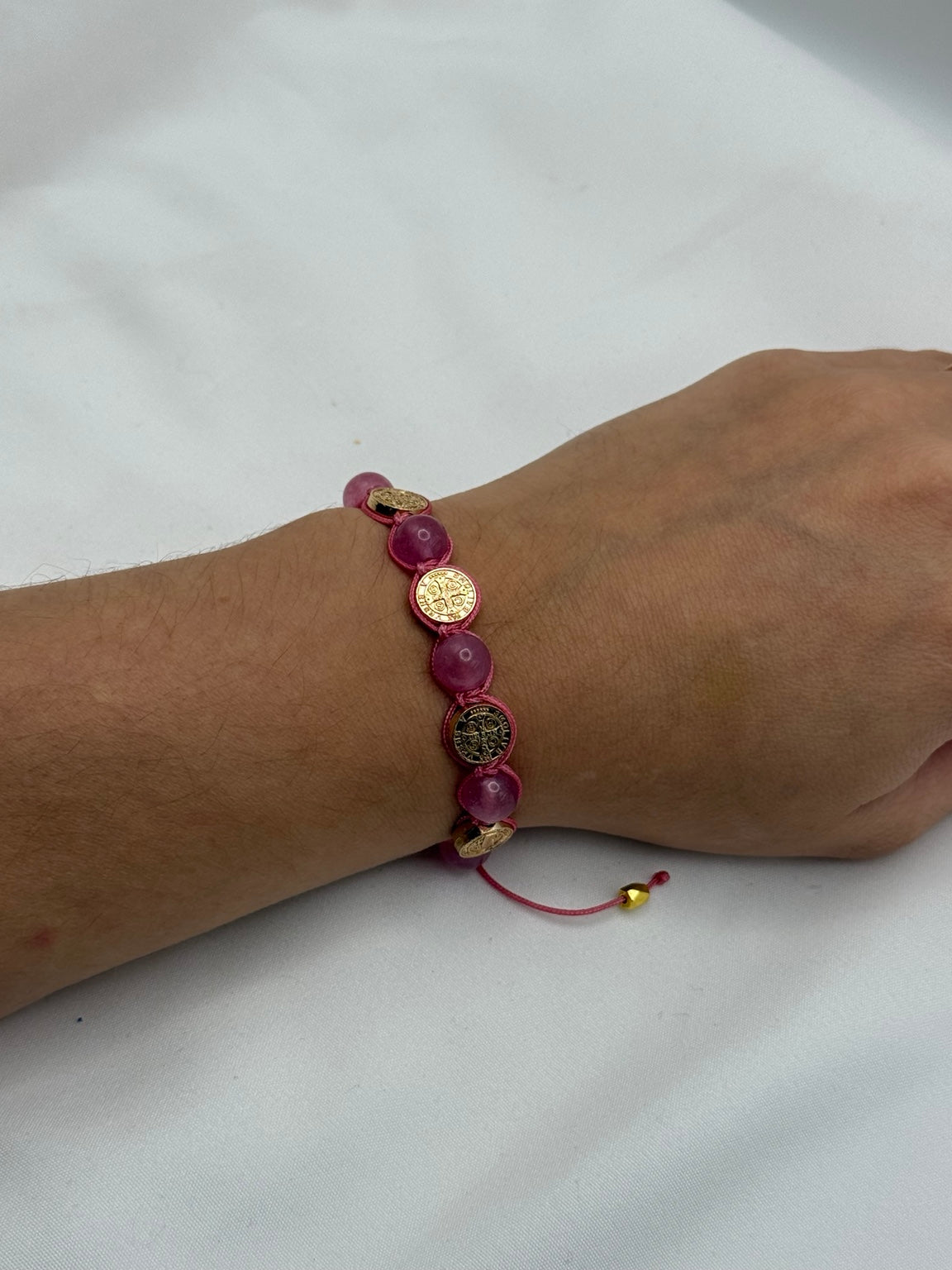 Pink and gold Saint Benedict medal adjustable Catholic bracelet shown on wrist