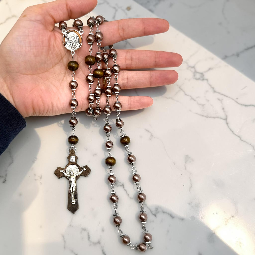 Purple pearl and wood Saint Benedict rosary shown in hand