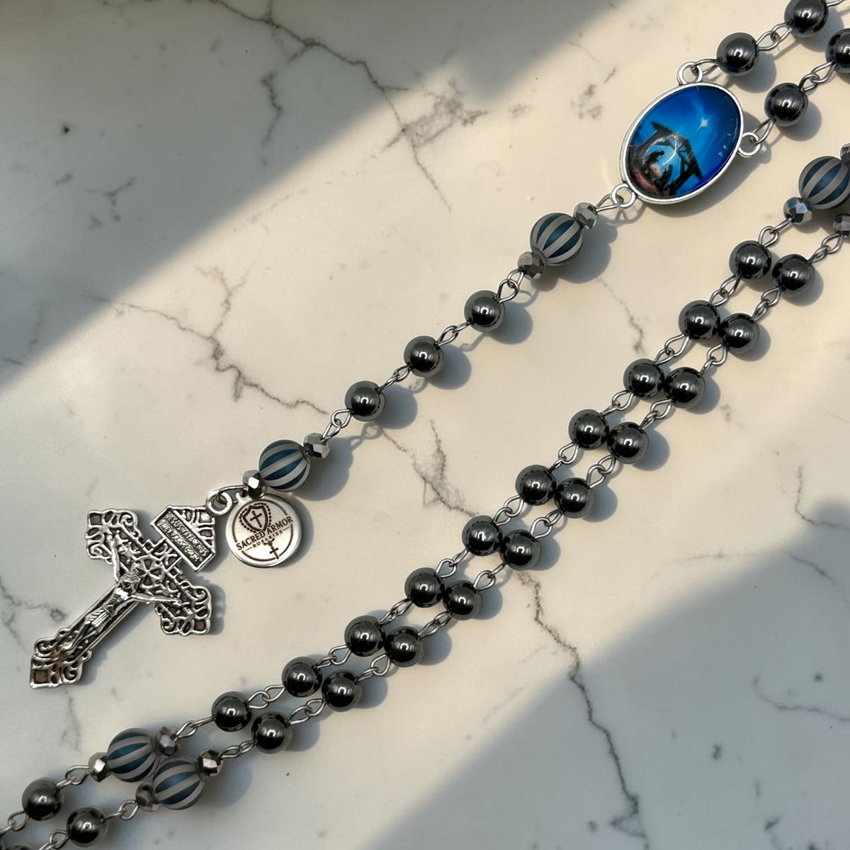 Close-up of dark gray hematite rosary with striped glass ornamental beads and Holy Night centerpiece