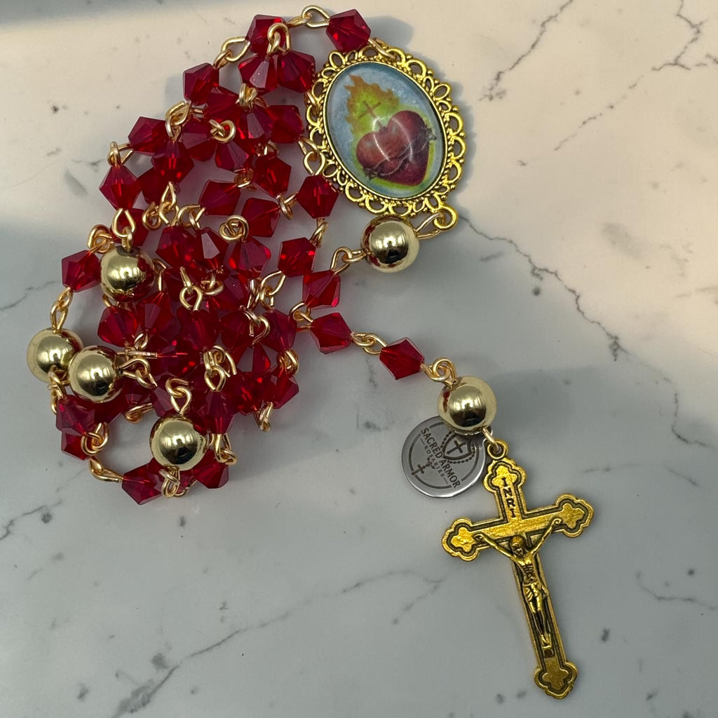 Close view of handmade red crystal rosary with ornate Sacred Heart centerpiece and gold-tone crucifix