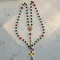 Black and red Catholic rosary with gold-tone links, Sacred Heart centerpiece, and purple-accented gold crucifix