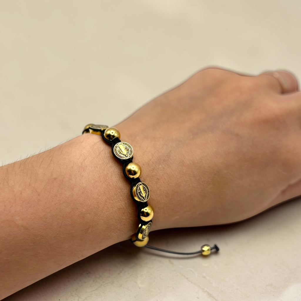 Gold and black St. Benedict medal adjustable bracelet worn on wrist