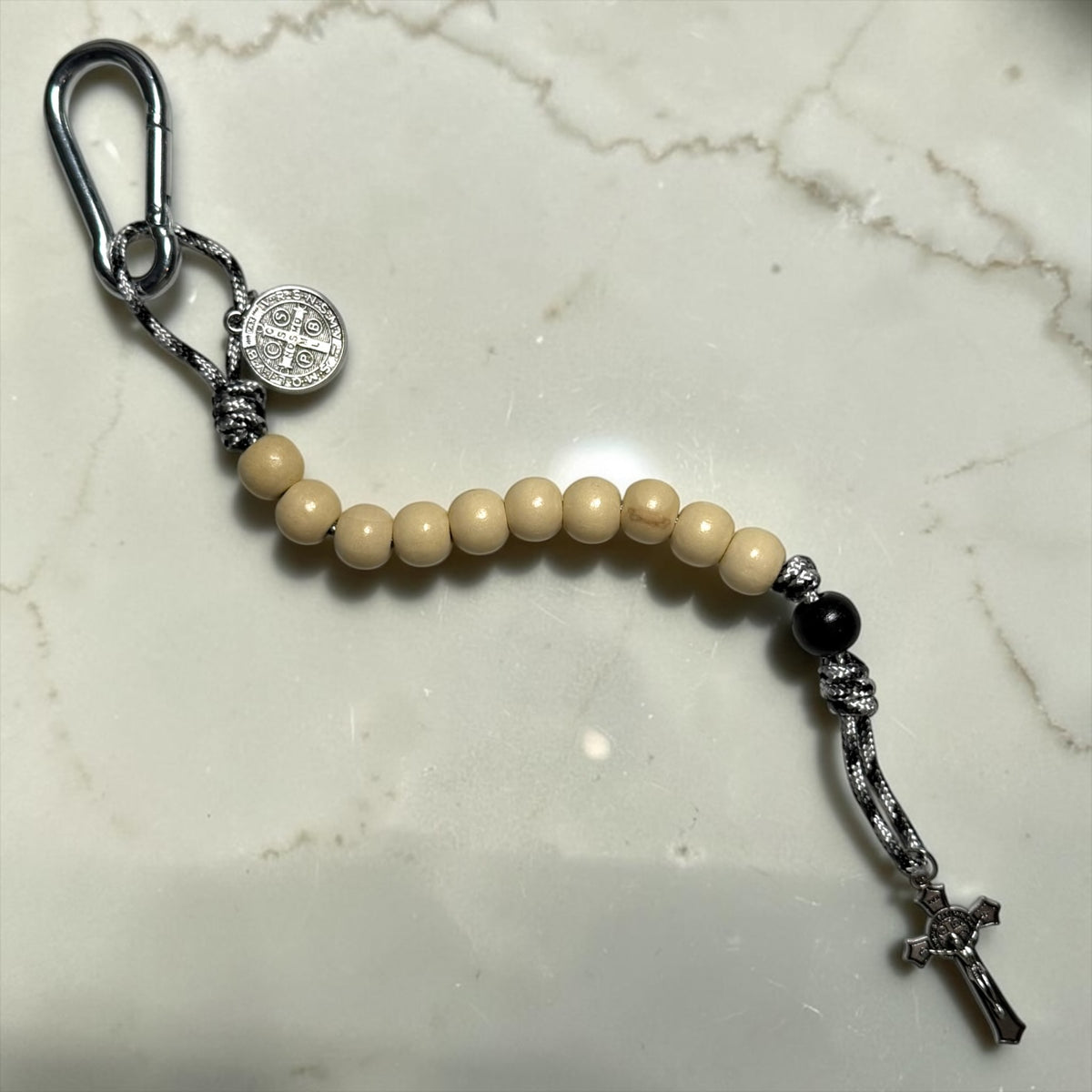 White wood and black St. Benedict pocket decade rosary with silver-tone carabiner and black-white paracord