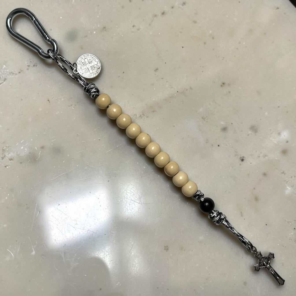 Full-length view of white wood and black St. Benedict pocket decade rosary with patterned paracord and silver-tone crucifix
