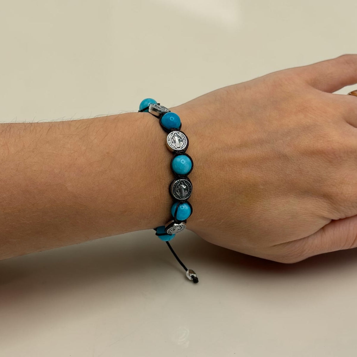 Turquoise-blue Saint Benedict medal bracelet shown on wrist